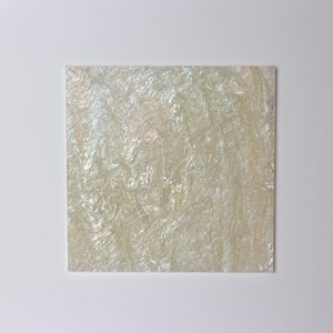 May include: A sheet of iridescent white mother of pearl, a material often used in jewelry and decorative crafts.