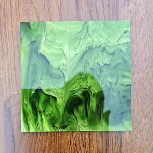 Puede incluir: Una lámina de acrílico verde y blanco con vetas y acabado brillante.