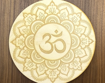 May include: A wooden round mandala with a carved Om symbol in the center. The mandala features intricate floral designs and patterns.