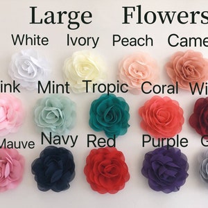 以下が含まれることがあります： Large Flowersというテキストと、White、Ivory、Peach、Cameo、Pink、Mint、Tropic、Coral、Wine、Rosy Mauve、Navy、Red、Purple、Greyという色名がラベル付けされた、グリッド状に配置された大きな布製の花。各花は層状の花びらで構成されています。