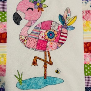 Peut inclure: Un bloc de quilt avec un flamant rose coloré. Le flamant rose est rose avec un corps en patchwork, un bec noir et une couronne florale. Il se tient dans un étang bleu avec de l'herbe verte et une petite abeille.