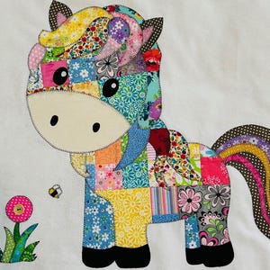 Puede incluir: Aplicación de caballo de patchwork colorido con un diseño caprichoso. El caballo presenta una variedad de telas florales y estampadas en tonos de rosa, azul, amarillo y verde. Una abeja y dos flores también están incluidas en el diseño.