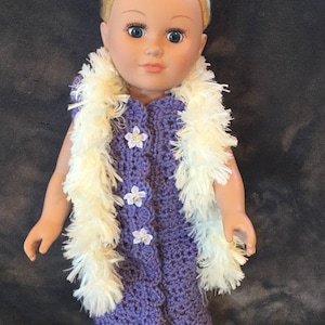 May include: A purple crocheted dress with white flower accents and a white fur scarf. The doll has blonde hair and blue eyes.