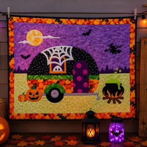 May include: A rectangular quilted wall hanging featuring a central graphic of a black camper trailer with a spiderweb, a purple door, and a ghost in the window. The scene includes a yellow moon, bats, a witch, and a black cauldron over a fire.