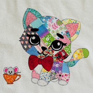 Op de afbeelding: Een kleurrijke patchwork kat met een rode vlinderdas en grote zwarte ogen. De kat is gemaakt van verschillende stoffen met patronen, waaronder bloemen- en stippenontwerpen. Een kleine muis in een oranje theekopje staat naast de kat.