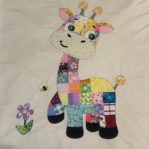 May include: A colorful patchwork giraffe applique with a smiling face, green eyes, and small ears. A bee and a flower are next to the giraffe. The giraffe is made of various patterned fabrics, including floral and geometric designs.