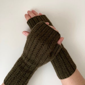 May include: A pair of olive green fingerless gloves made of knitted wool. The gloves are folded over and the cuffs are visible.