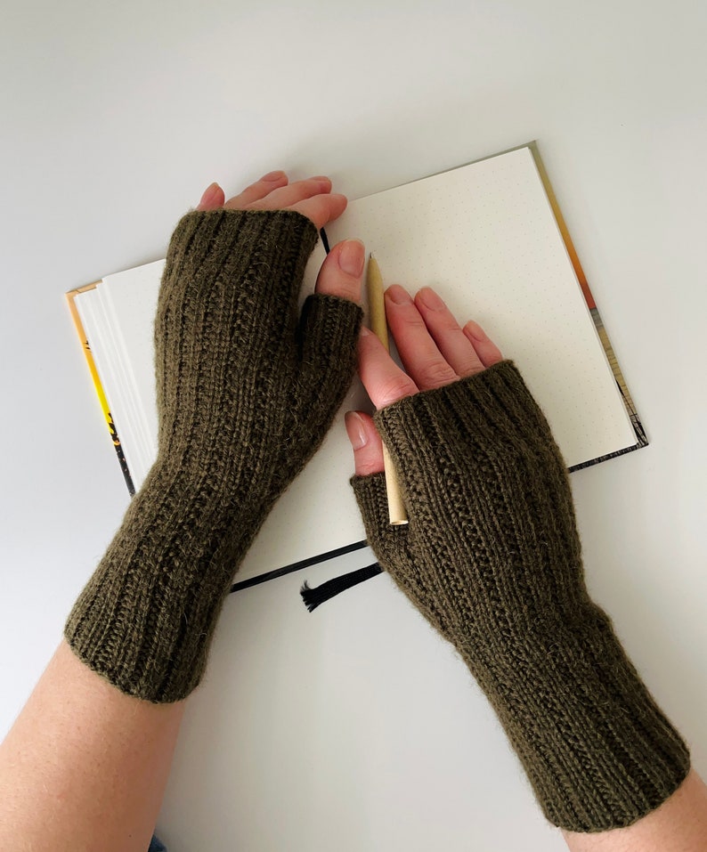 May include: A pair of olive green fingerless knitted gloves. The gloves are made of a soft, warm material and are perfect for keeping your hands warm in the winter.