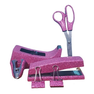 May include: Pink glitter desk set with a stapler, staple remover, scissors, and binder clips.