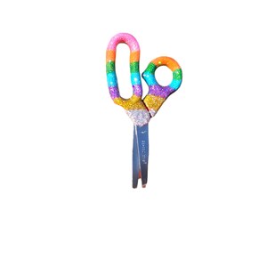 May include: Rainbow glitter scissors with silver blades. The handles are decorated with a rainbow of glitter colors, including pink, orange, yellow, green, blue, purple, and silver.