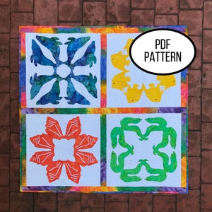Könnte beinhalten: Ein farbenfroher Quilt mit vier weißen Quadraten, die jeweils ein einzigartiges Design aufweisen. Die Designs umfassen blaue Wale, gelbe Fische, orangefarbene Meereskreaturen und grüne Aale. Der Quilt ist mit einem Regenbogenmuster eingefasst und enthält den Text "PDF PATTERN".