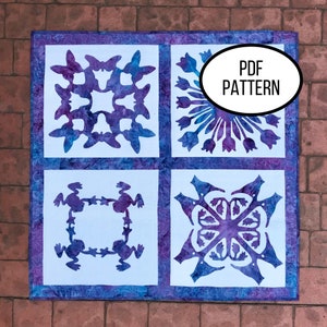 May include: A PDF pattern for a quilt featuring four different designs: a snowflake, a flower, a frog, and a geometric pattern. The designs are cut out of white fabric and placed on a purple and blue fabric background.