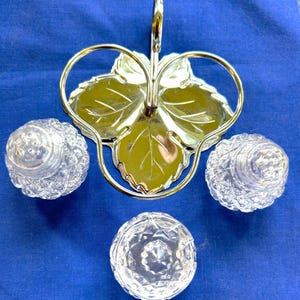 May include: A silver leaf-shaped serving tray with three clear glass salt and pepper shakers.