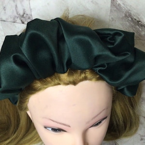 Peut inclure: Un chouchou en satin vert foncé pour les cheveux. Le chouchou est rassemblé et bouffant pour créer une forme large et gonflée.