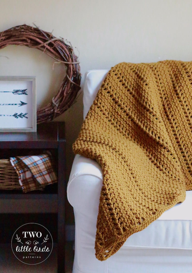 Pu&ograve; includere: Una coperta in crochet color giallo senape drappeggiata su una poltrona bianca. La coperta ha un semplice motivo a punto ed &egrave; realizzata con un filato morbido. La coperta &egrave; un'aggiunta accogliente a qualsiasi soggiorno.