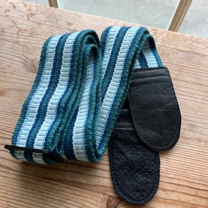 May include: A blue and white striped guitar strap with black leather ends.