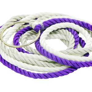 May include: A coiled length of thick, twisted rope featuring alternating sections of bright white and vibrant purple fibers, secured by a smooth, circular silver-toned metal ring that holds the rope in a looped configuration.