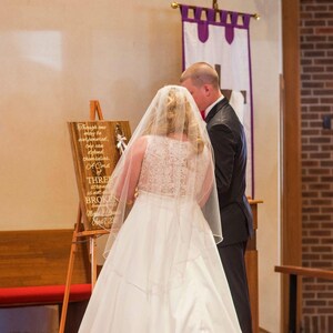 May include: A wooden sign on a tripod easel featuring the text: Though one may be overpowered, two can defend themselves. A Cord of THREE strands is not easily BROKEN. Ecclesiastes 4:12. Michael & Amanda April 7, 2018. The sign has three braided cords.