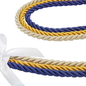 May include: Close-up of decorative rope in three colors: navy blue, gold, and cream. A white satin ribbon is tied in a bow at the end of the rope. The rope is tightly twisted, and the colors are vibrant against the white background.