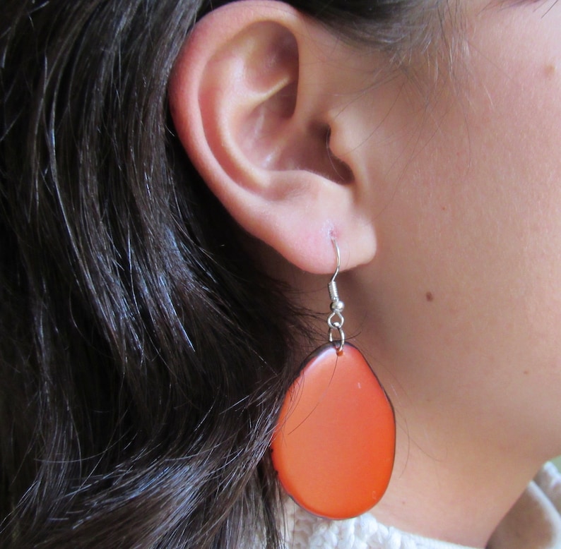 May include: A pair of orange, oval-shaped earrings with silver hooks.
