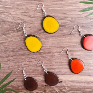 May include: A set of six earrings with wooden bases and colorful resin inlays. The earrings are in three different colors: yellow, red, and brown.
