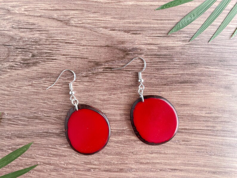 May include: A pair of red and black resin earrings with silver hooks. The earrings are oval shaped and have a smooth, glossy finish.