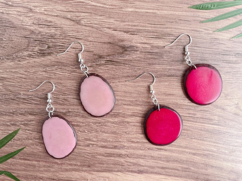 May include: Three pairs of earrings with a wood-like design. The earrings are made of resin and have a pink, red, and light pink color.