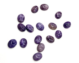 May include: A collection of fifteen oval-shaped cabochons made of purple charoite stone. Each piece features a smooth, polished surface with distinct swirling patterns of deep violet, lavender, and white mineral inclusions throughout the stones.