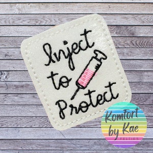 May include: White felt square patch with black embroidery that reads "Inject to Protect" and a pink and white syringe illustration.