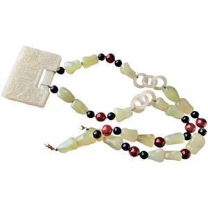 May include: A jade necklace with a carved jade pendant, black and red beads, and a white jade clasp.
