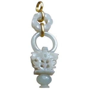 May include: A white jade pendant with a gold loop and a carved floral design. The pendant is attached to a gold chain.