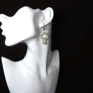 May include: A pair of white jade earrings with a silver hook and a double loop design.