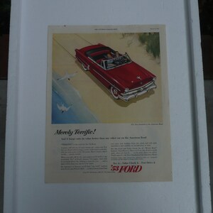 May include: A vintage advertisement for the 1953 Ford car. The ad features a red convertible driving on a sandy beach with a couple inside. The text reads "Merely Terrific!" and "'53 Ford.  See it.  Value Check it.  Test Drive it."