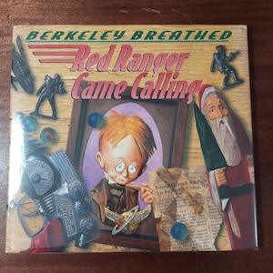 May include: A book cover for "Red Ranger Came Calling" by Berkeley Breathed. The cover features a cartoon illustration of a boy, Santa Claus, and toy soldiers. The title is in red and the background is wood-like.