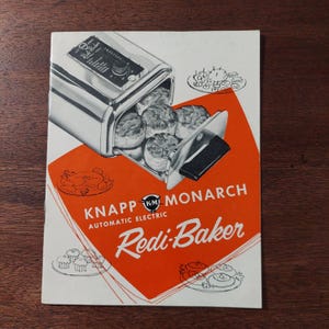 May include: Vintage advertisement for the Knapp Monarch Redi-Baker, an automatic electric appliance. The image shows the appliance with baked goods inside, set against a white and orange background. The text "Redi-Baker" is prominently displayed.