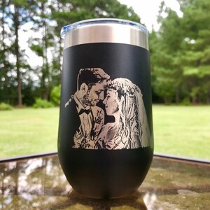 May include: Black stainless steel tumbler with a laser engraved image of a couple in a wedding setting. The image is in silver.
