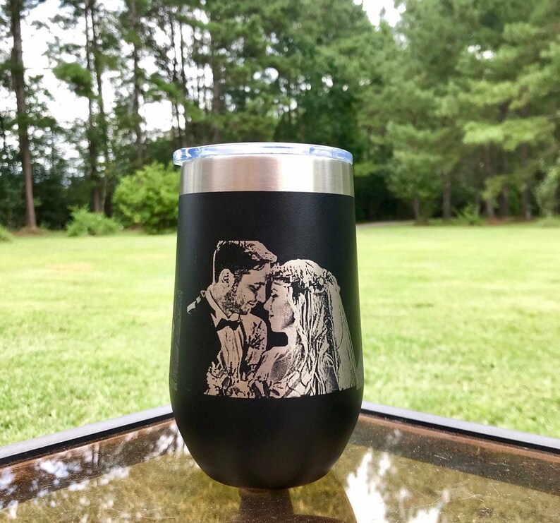 May include: Black stainless steel tumbler with a laser engraved image of a couple on their wedding day. The image shows the couple looking at each other and smiling.