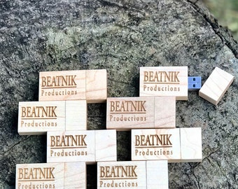 May include: A collection of eight wooden USB flash drives with the text "BEATNIK Productions" engraved on each one. The flash drives are arranged in a staggered pattern on a wooden surface.
