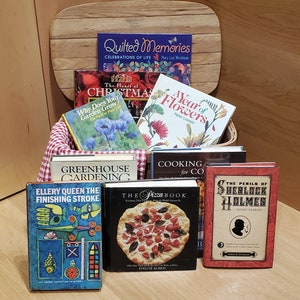 May include: A basket filled with a variety of books, including "The Heart of Christmas", "A Year of Flowers", "Greenhouse Gardening", "The Pizza Book", "Ellery Queen The Finishing Stroke", and "The Perils of Sherlock Holmes".