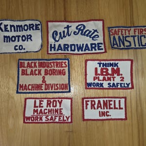 May include: Collection of vintage embroidered patches with text. Patches include "Kenmore Motor Co.", "Cut Rate Hardware", "Safety First Anstice", "Black Industries Machine Division", "Think I.B.M. Plant 2 Work Safely", "Le Roy Machine Work Safely", and "Franell Inc."