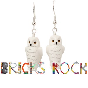 May include: A pair of white owl earrings made from LEGO bricks. The earrings are hanging from silver hooks. The word "BRICKS ROCK" is spelled out below the earrings using LEGO bricks.