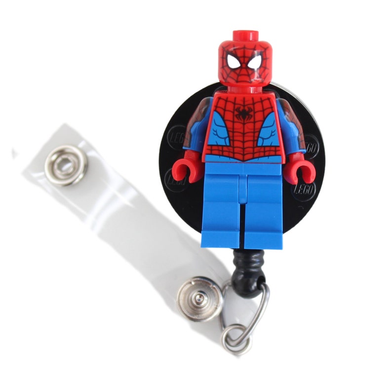 May include: A red and blue Lego minifigure of Spiderman with a black web design on the chest, attached to a black retractable badge reel with a clear plastic clip.