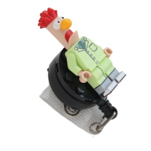 May include: A green and white Lego minifigure of a rooster wearing a suit, attached to a black retractable badge reel.