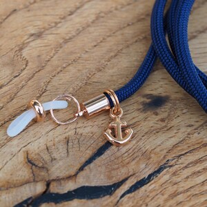 Op de afbeelding: Een marineblauwe brilketting met een gouden ankerbedel en transparante siliconen oorhaken.