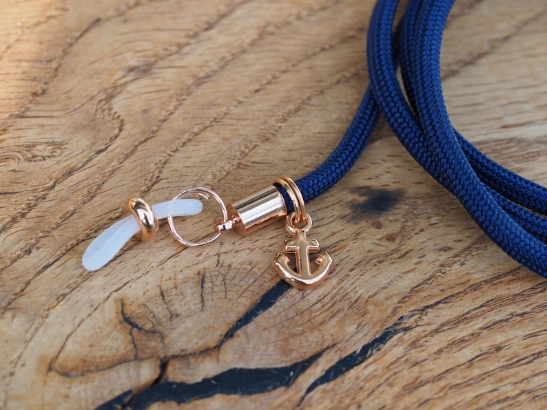 Op de afbeelding: Een marineblauwe brilketting met een gouden ankerbedel en transparante siliconen oorhaken.