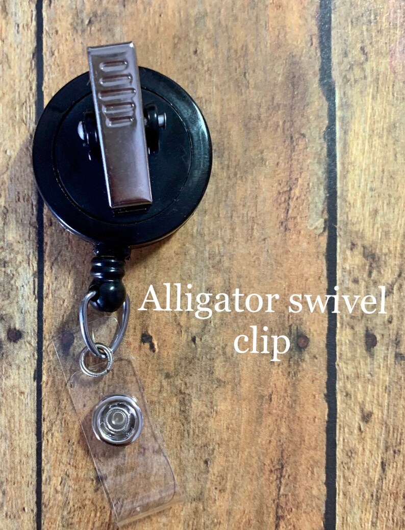 May include: Black retractable badge reel with an alligator swivel clip and a clear plastic strap with a snap closure. The text "Alligator swivel clip" is printed on the image.