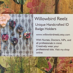May include: A business card with the text "Willowbird Reelz Unique Handcrafted ID Badge Holders" and a website address. The card displays several unique ID badge holders with decorative designs. The background is a floral pattern.