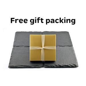 May include: A gold gift box tied with a sheer ribbon, presented on a set of four dark gray slate tiles. The text "Free gift packing" is displayed in black above the box.