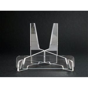 May include: A clear acrylic display stand with a triangular shape. The stand is designed to hold a plate or other flat object.
