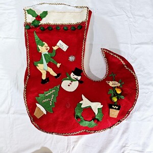 May include: A vintage red Christmas stocking with felt appliqués. The stocking features an elf, snowman, Christmas tree, wreath, and a bird with fruit. The top is white with green holly and gold trim.
